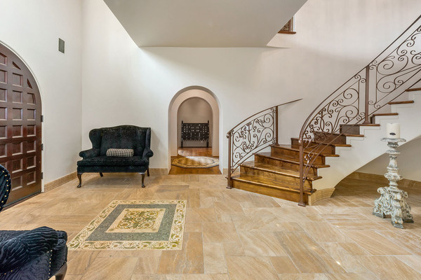 ورودی خانه به سبک کلاسیک تزئین شده و دو مبل راحتی در دو طرف در قرار داده شده است.